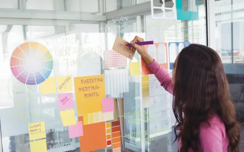 person brainstorming design solutions on a dry erase board